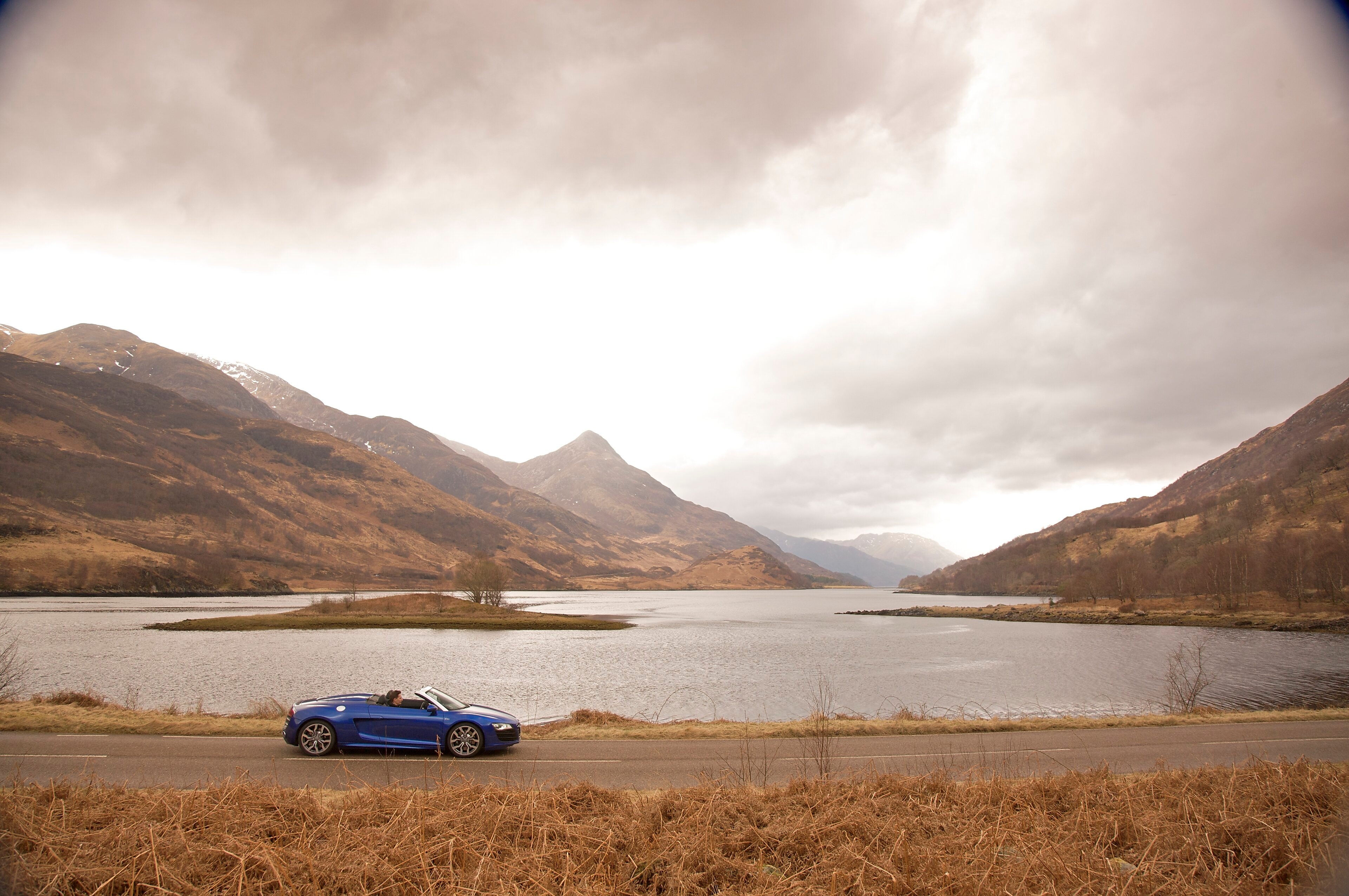 Car on the road by a mountain lake